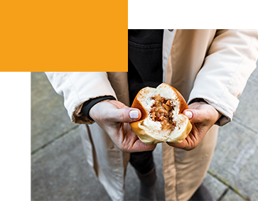 Hands opening a pork bun from Dim Sum King