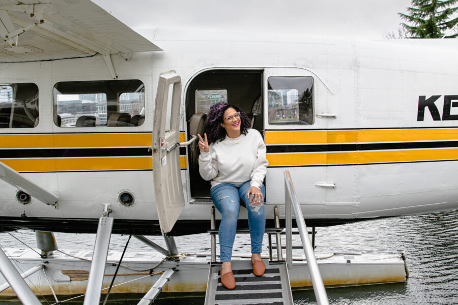 Woman sitting on the steps of a Kenmore Air seaplane at dock.