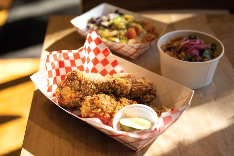 A basket of fried chicken lined with red and white checkered paper.
