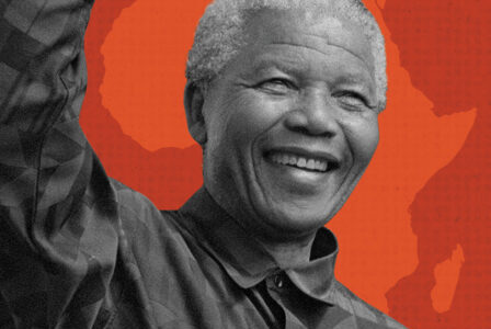A smiling man with short gray hair raises his right arm. He wears a patterned shirt, and the background features a red map outline of Africa.