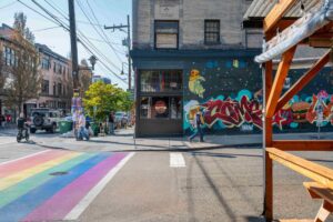 A vibrant city street corner with a rainbow crosswalk.
