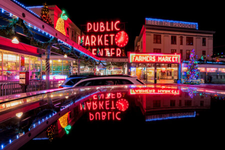 Nighttime view of Seattle’s Pike Place Market lit with colorful neon signs, including 