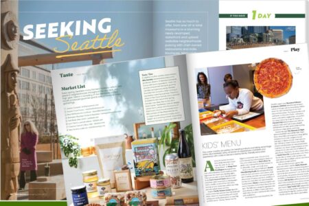 An open magazine spread features Seattle highlights, including local food items, a woman standing by a wooden totem, a pizza, and a chef helping a child in a kitchen. Articles and images explore taste, dining, and family activities.