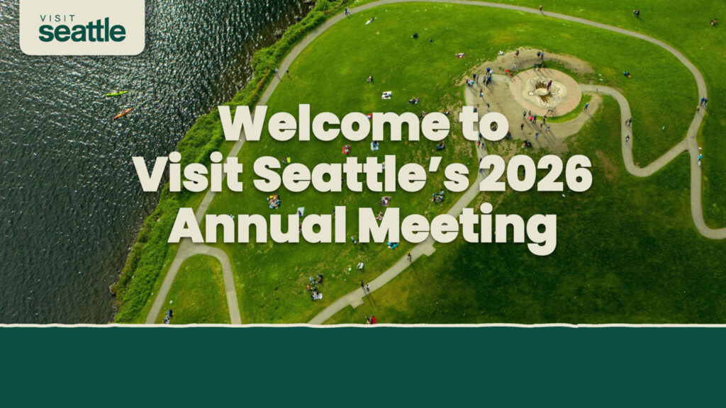Aerial view of a park by the water with people gathered around a central feature. Large text reads: "Welcome to Visit Seattle’s 2026 Annual Meeting." Visit Seattle logo in the top left corner.