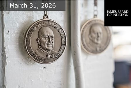 Close-up of a James Beard Foundation medal hanging on a white wall, with another blurred medal in the background. Text reads "March 31, 2026" and the James Beard Foundation logo appears in the corner.