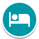 A white icon of a person lying in a bed, shown on a teal circular background, representing accommodation or a place to sleep.